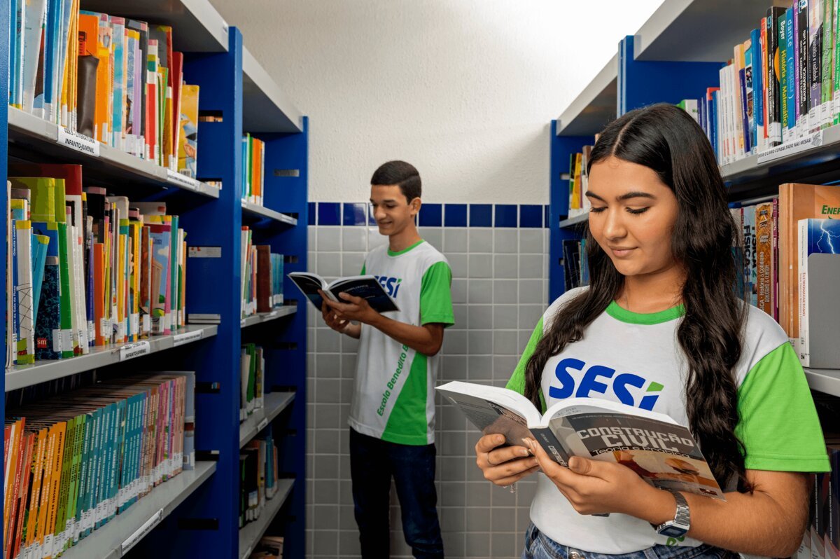 Estudantes pesquisando entre as estantes da biblioteca